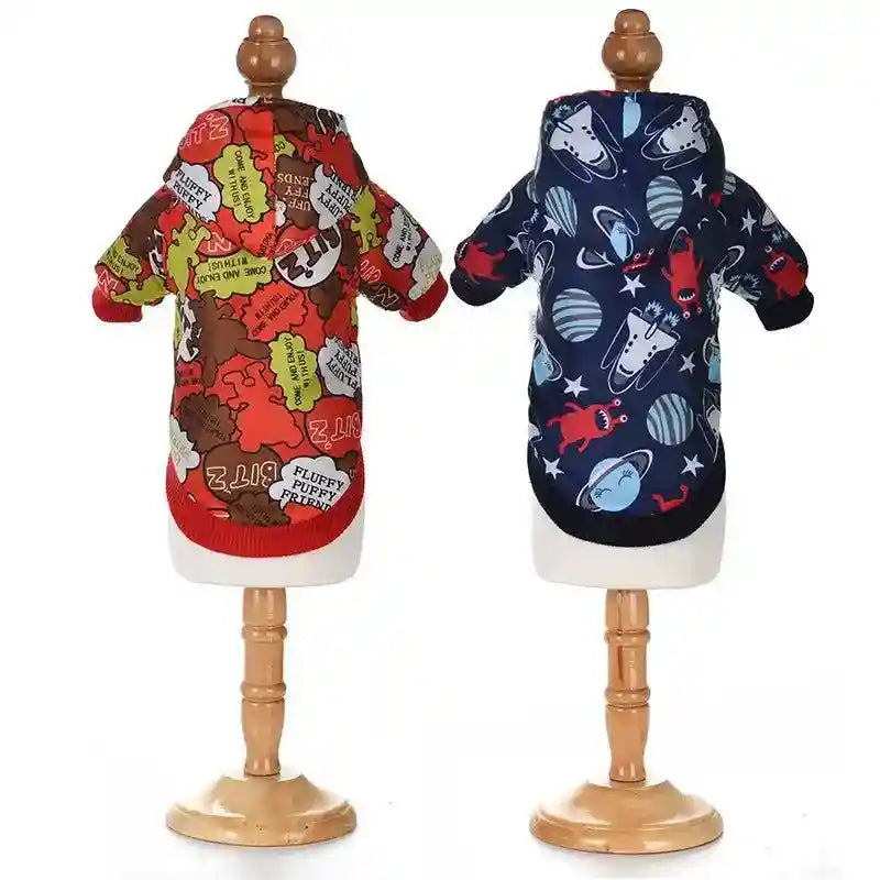 Two colorful dog hoodies with cartoon and text prints displayed on wooden mannequins