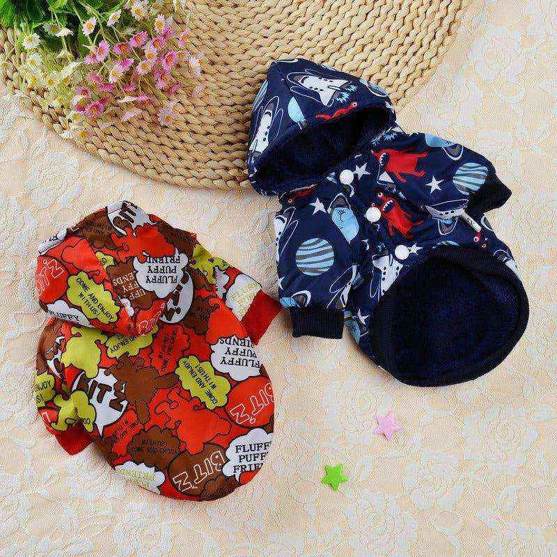 Two small dog hooded jackets on a lace surface, one with colorful cartoon text and the other navy blue with space and dinosaur prints