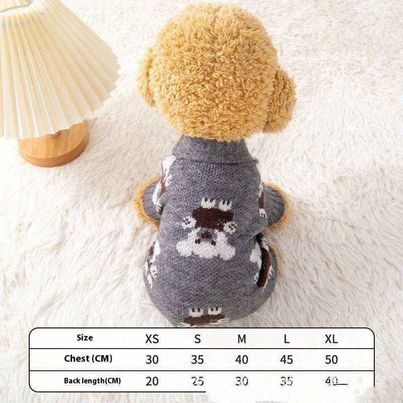 Small dog wearing gray bear-patterned knit cardigan sitting on white fur rug next to beige lamp