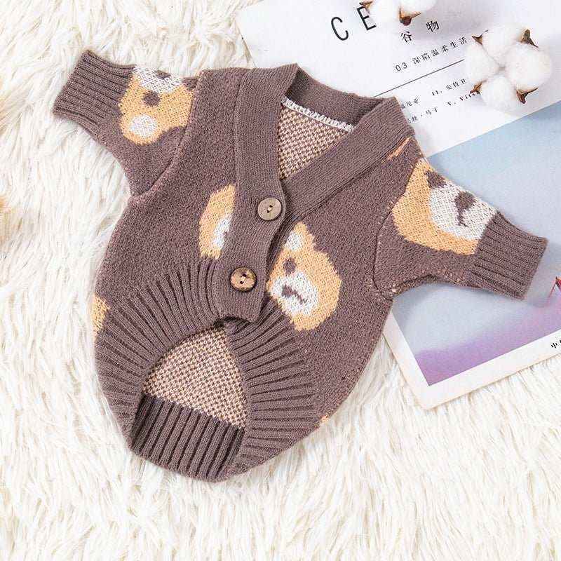Brown knitted dog cardigan with bear face pattern and wooden buttons on white rug