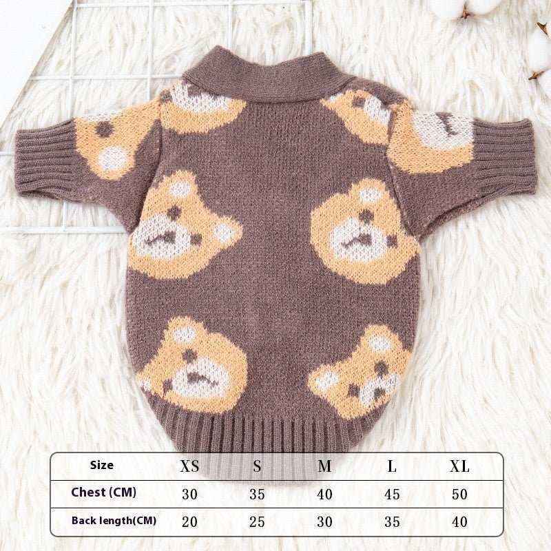 Brown knitted dog cardigan with cute teddy bear pattern, lying flat on a white furry surface with size chart