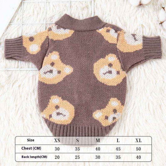 Brown knitted dog cardigan with cute teddy bear pattern, lying flat on a white furry surface with size chart