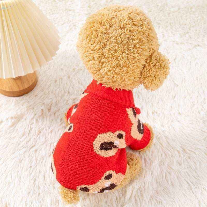 Small curly dog wearing a red sweater with teddy bear pattern sitting on a white fluffy rug