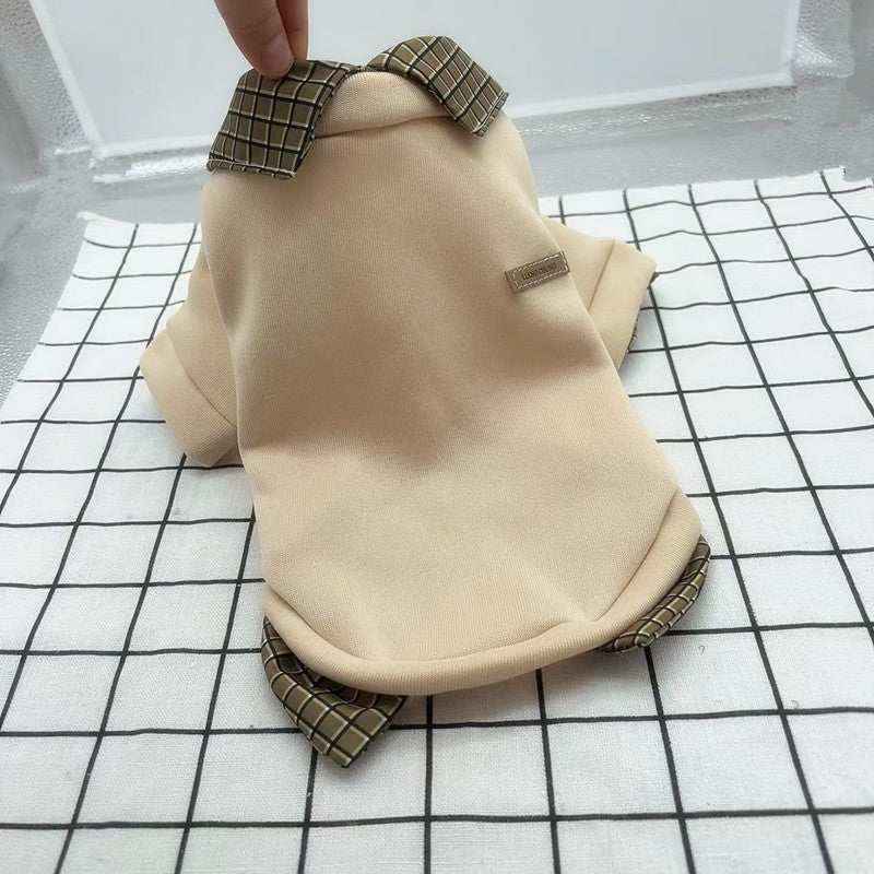 Beige pet shirt with checkered collar and trim laid on black and white grid fabric