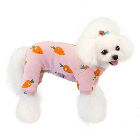 White poodle wearing pink dog pajamas with orange carrot prints and a blue flower hair clip