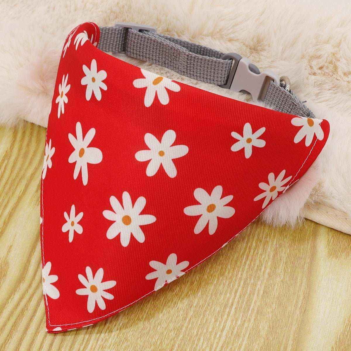 Red dog bandana with white daisy flower pattern and gray nylon collar on wooden surface