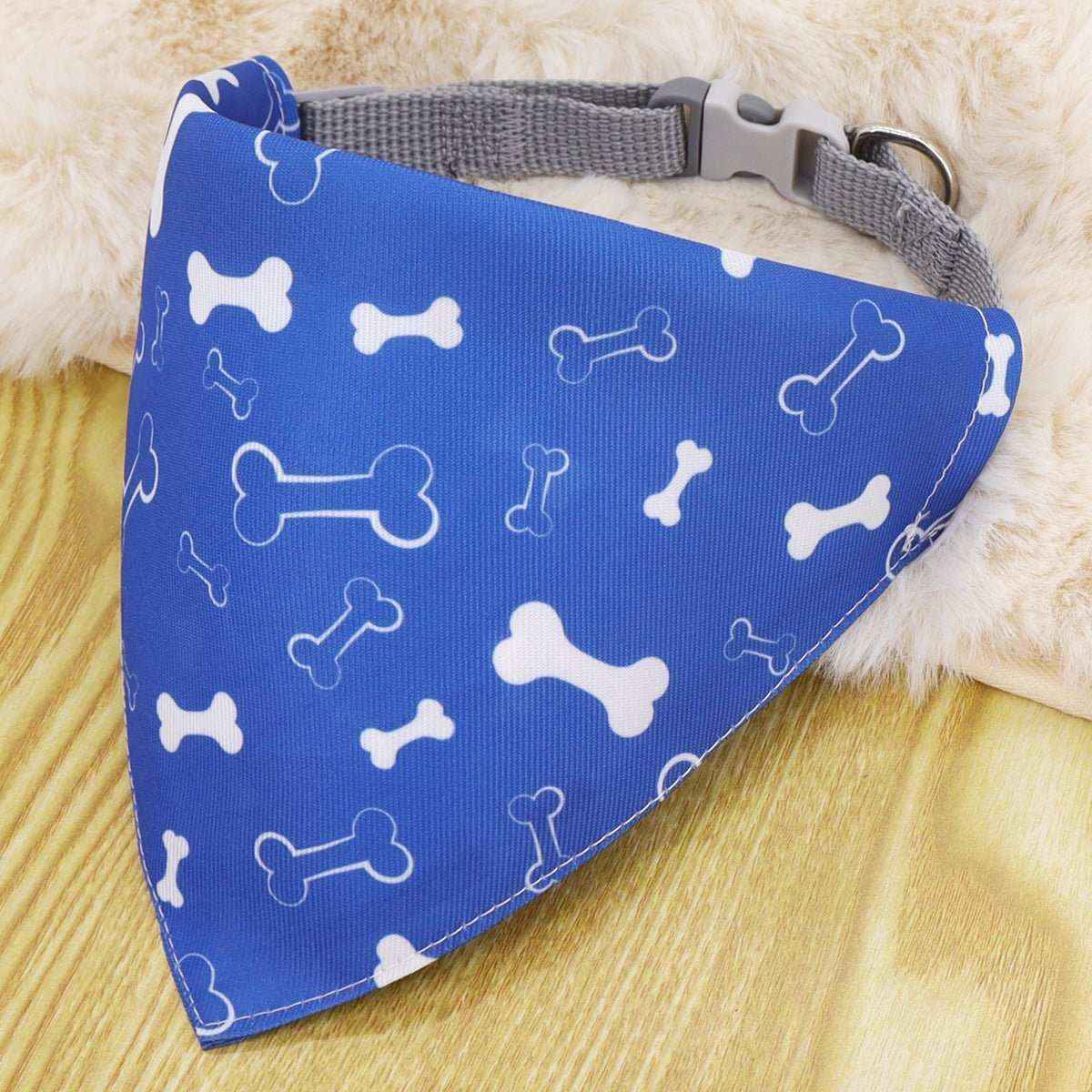 Blue dog bandana with white bone pattern attached to grey nylon collar on wooden surface