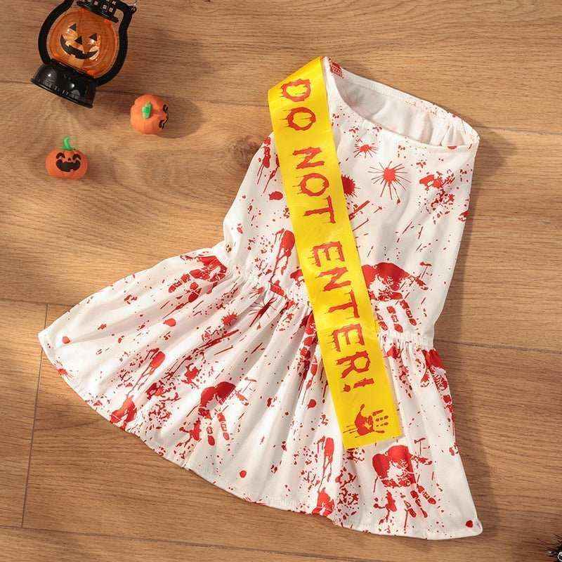 White Halloween dog costume with red fake blood splatters and yellow Do Not Enter sash on wooden floor