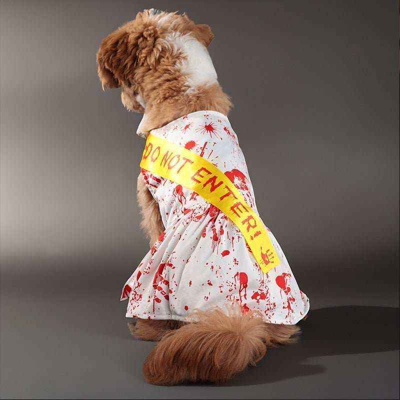 small brown dog wearing white Halloween costume with fake blood splatters and yellow 'Do Not Enter' sash