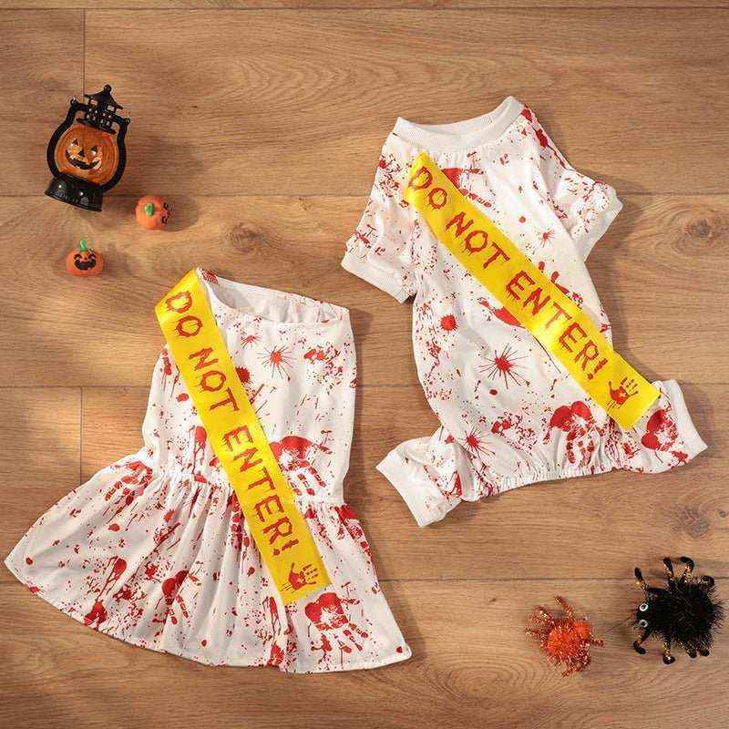 White Halloween dog costumes with fake blood splatters and yellow Do Not Enter sashes on wooden floor
