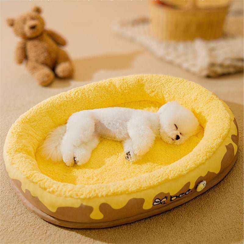 Small white fluffy dog peacefully sleeping in a yellow honey-themed cozy pet bed with teddy bear in background