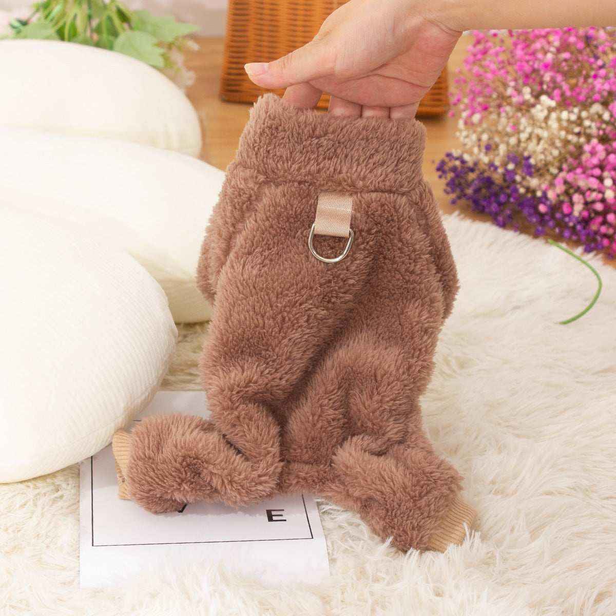 Hand holding brown fluffy dog sweater with metal ring, soft cozy pet clothing