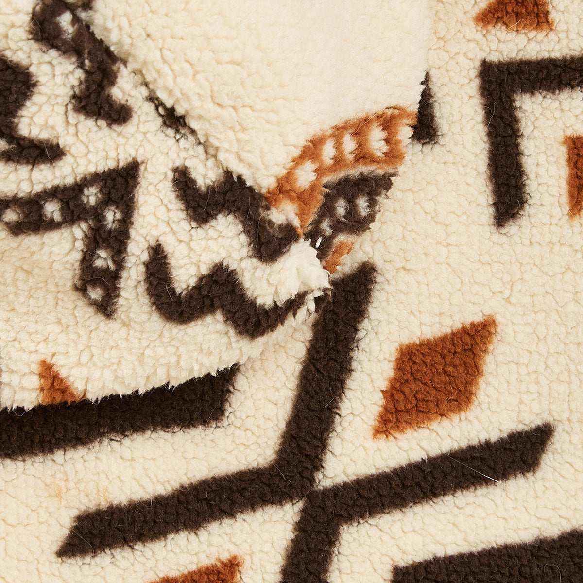 Close-up of soft fleece fabric with cream, brown, and rust geometric tribal patterns