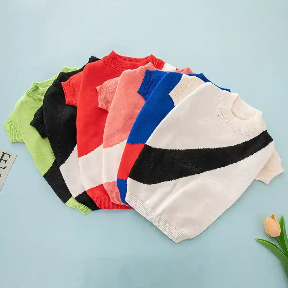 Colorful knitted dog sweaters in green, black, red, pink, blue, and white with black stripe on light blue background