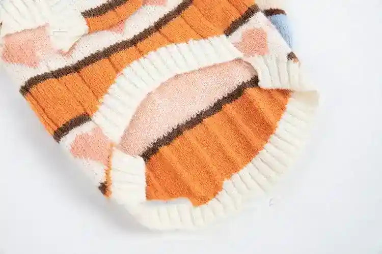 Close-up of a soft, orange and white striped knit sweater with ribbed cuffs and geometric patterns