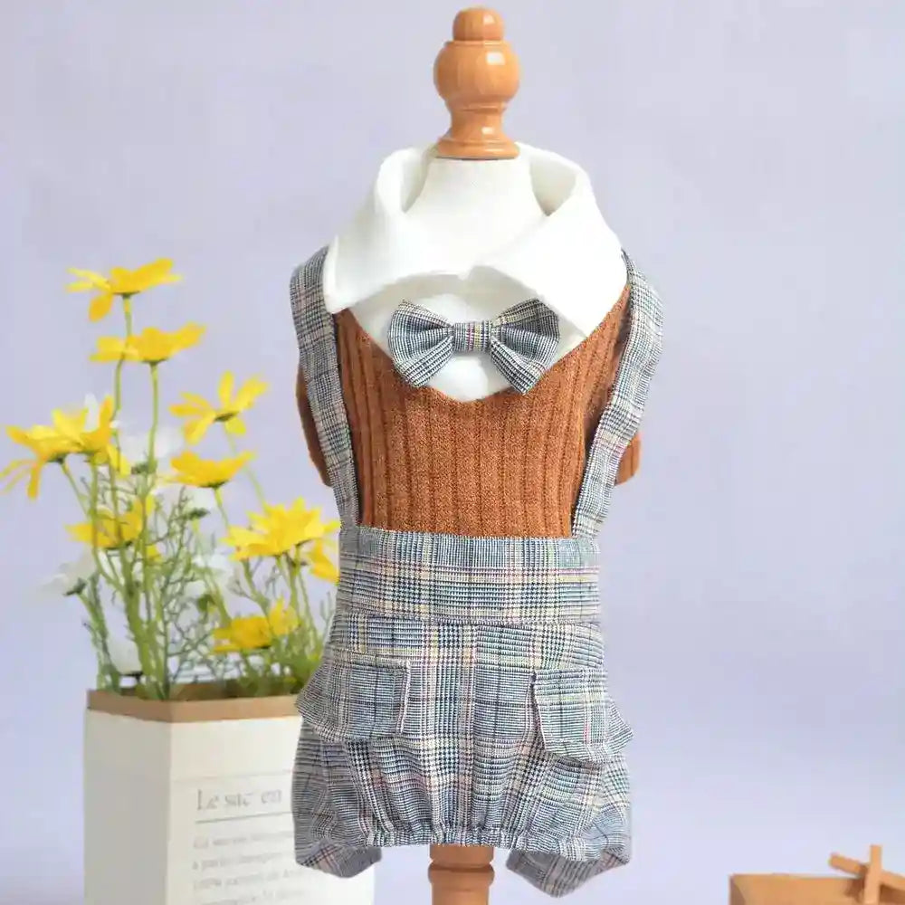 Brown sweater and checkered suspender shorts with bowtie on a mannequin, yellow flowers in the background