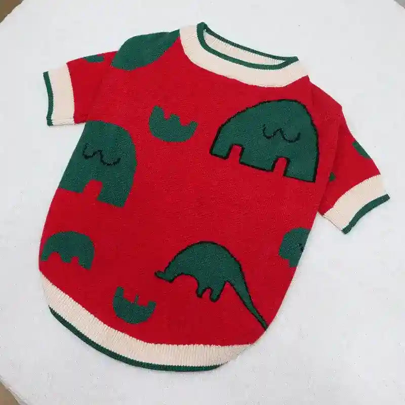 Red knitted baby sweater with green dinosaur patterns and white trim on collar and sleeves