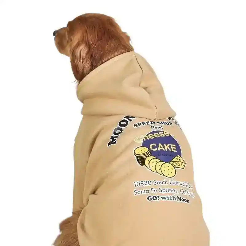 Golden retriever wearing beige dog hoodie with cheese cake graphic and text on back