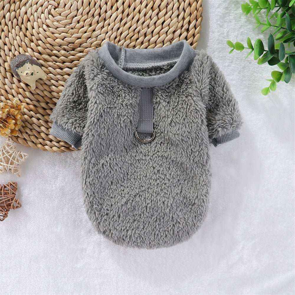 Gray fleece dog sweater with harness ring on white surface with decorative plants and toys