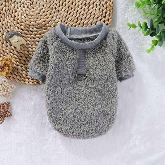 Gray fleece dog sweater with harness ring on white surface with decorative plants and toys