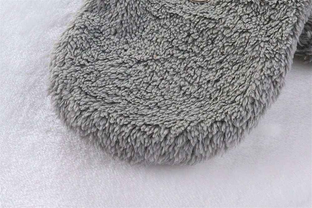 Close-up of a soft gray plush pet blanket or cozy dog bed on a light surface