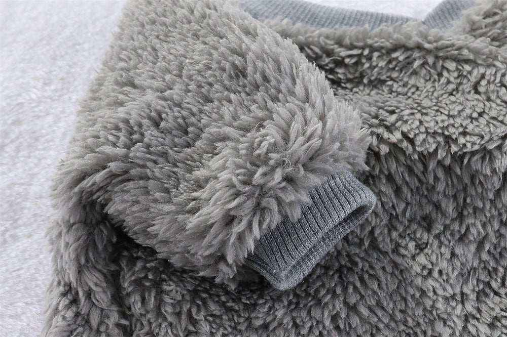 Close-up of soft gray fuzzy fleece fabric with ribbed cuff detail on a cozy textured surface