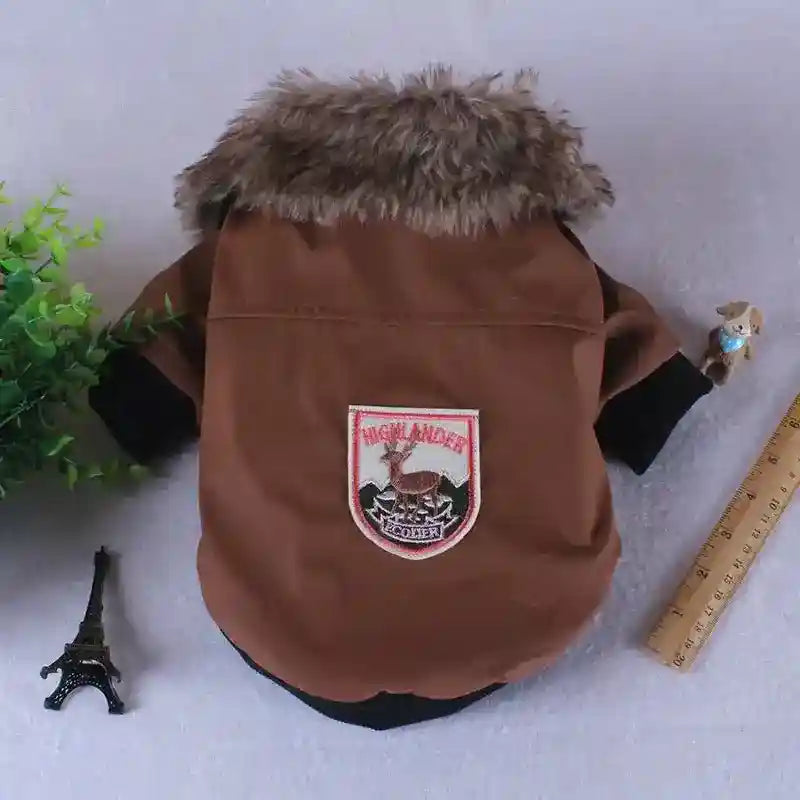 Brown dog jacket with faux fur collar and Highlander patch, displayed with ruler and mini Eiffel Tower