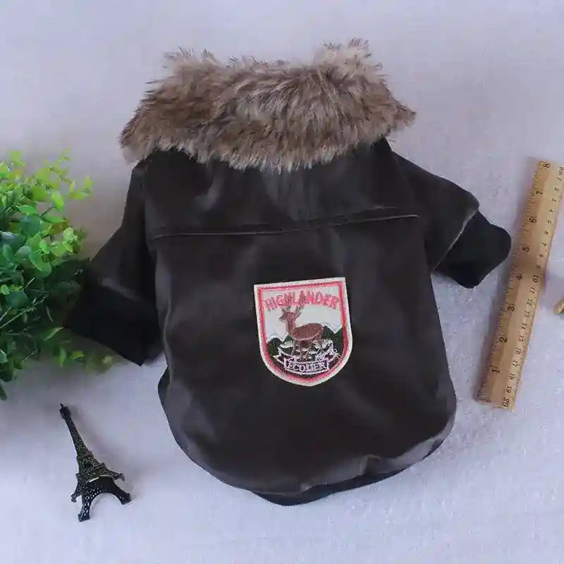 Black dog jacket with faux fur collar and Highlander embroidered patch, ruler and small Eiffel Tower model nearby