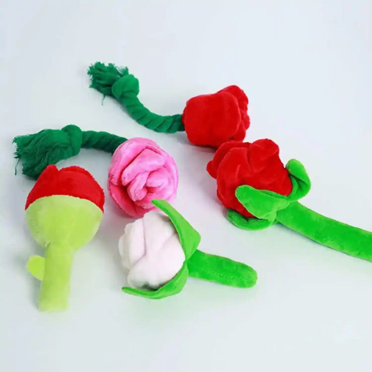 Set of plush flower-shaped dog and cat chew toys with green stems and vibrant red, pink, and white petals on white background