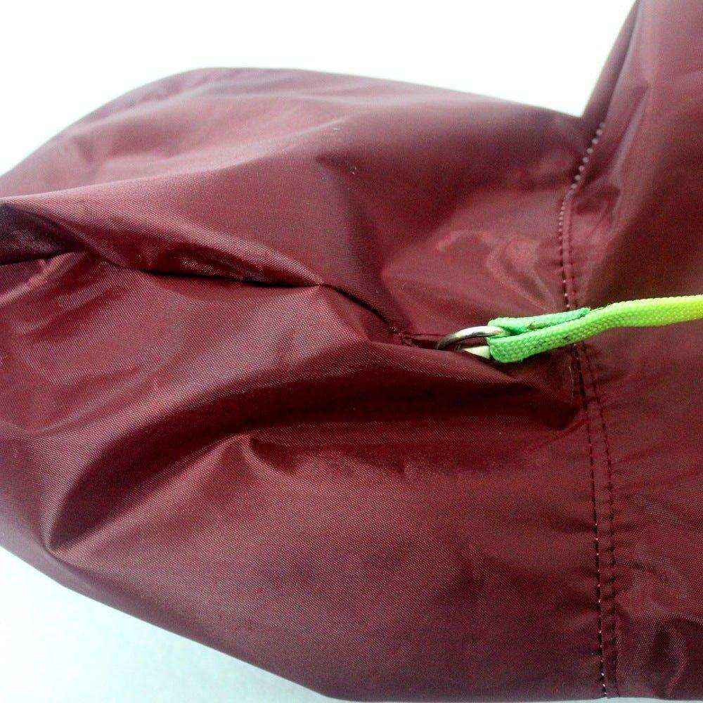 Close-up of maroon dog raincoat fabric with green leash loop and stitching detail
