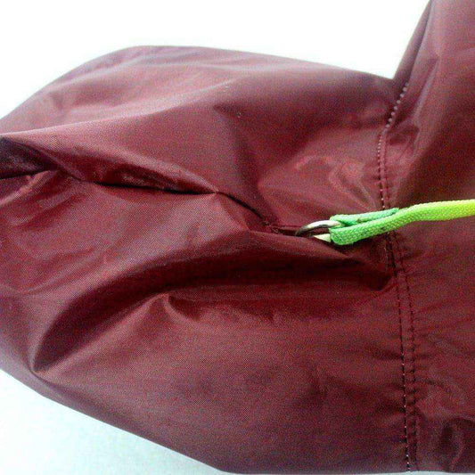 Close-up of maroon dog raincoat fabric with green leash loop and stitching detail