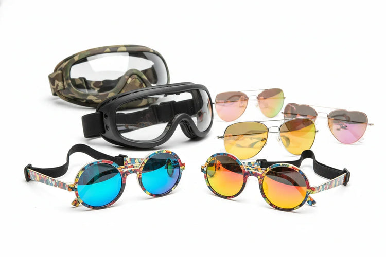 Six pairs of sunglasses and goggles for dogs, including colorful round frames and mirrored aviators