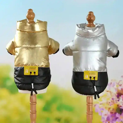 Gold and silver padded dog jackets with black bottoms on wooden mannequins against a floral background