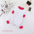 White pet jumpsuit with blue bear head and footprint pattern, red cuffs and collar, cotton branch, mini chalkboard on white background