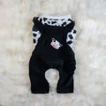 Black corduroy overalls with cow patch and white cow print shirt on fluffy white background