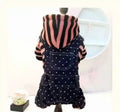 Pet outfit with pink and black striped hoodie and navy blue polka dot overalls on mannequin