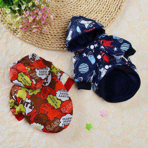 Two small dog hooded jackets on a lace surface, one with colorful cartoon text and the other navy blue with space and dinosaur prints