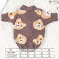 Brown knitted dog cardigan with cute teddy bear pattern, lying flat on a white furry surface with size chart