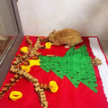 Small brown rabbit on a red Christmas-themed play mat with green tree and yellow decorations